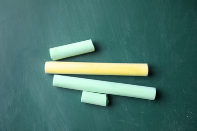 Pieces of color chalk on greenboard, flat lay