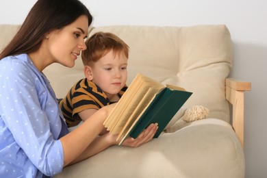 Photo of Mother reading book with her son in living room at home