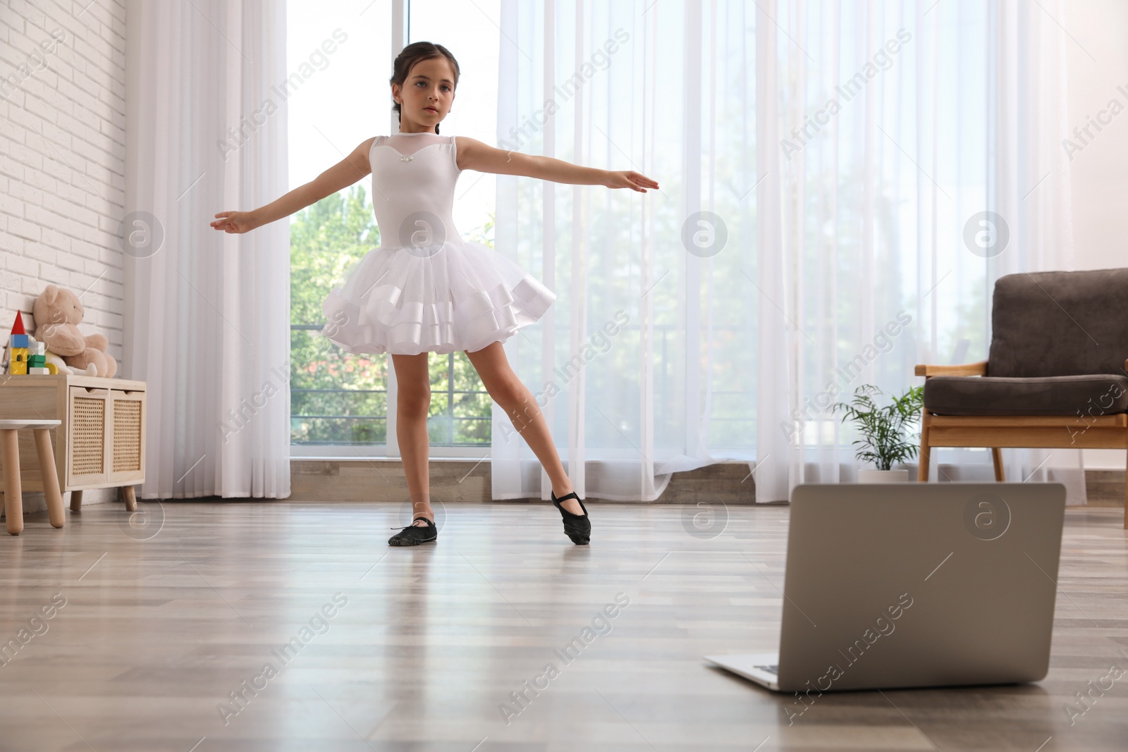 Photo of Cute little girl taking online dance class at home