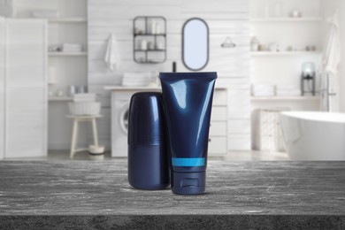 Image of Deodorant and tube of cream on grey table in bathroom. Mockup for design