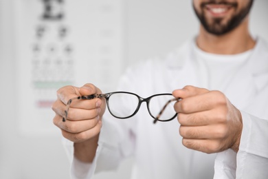 Photo of Male ophthalmologist with eyeglasses in clinic, closeup