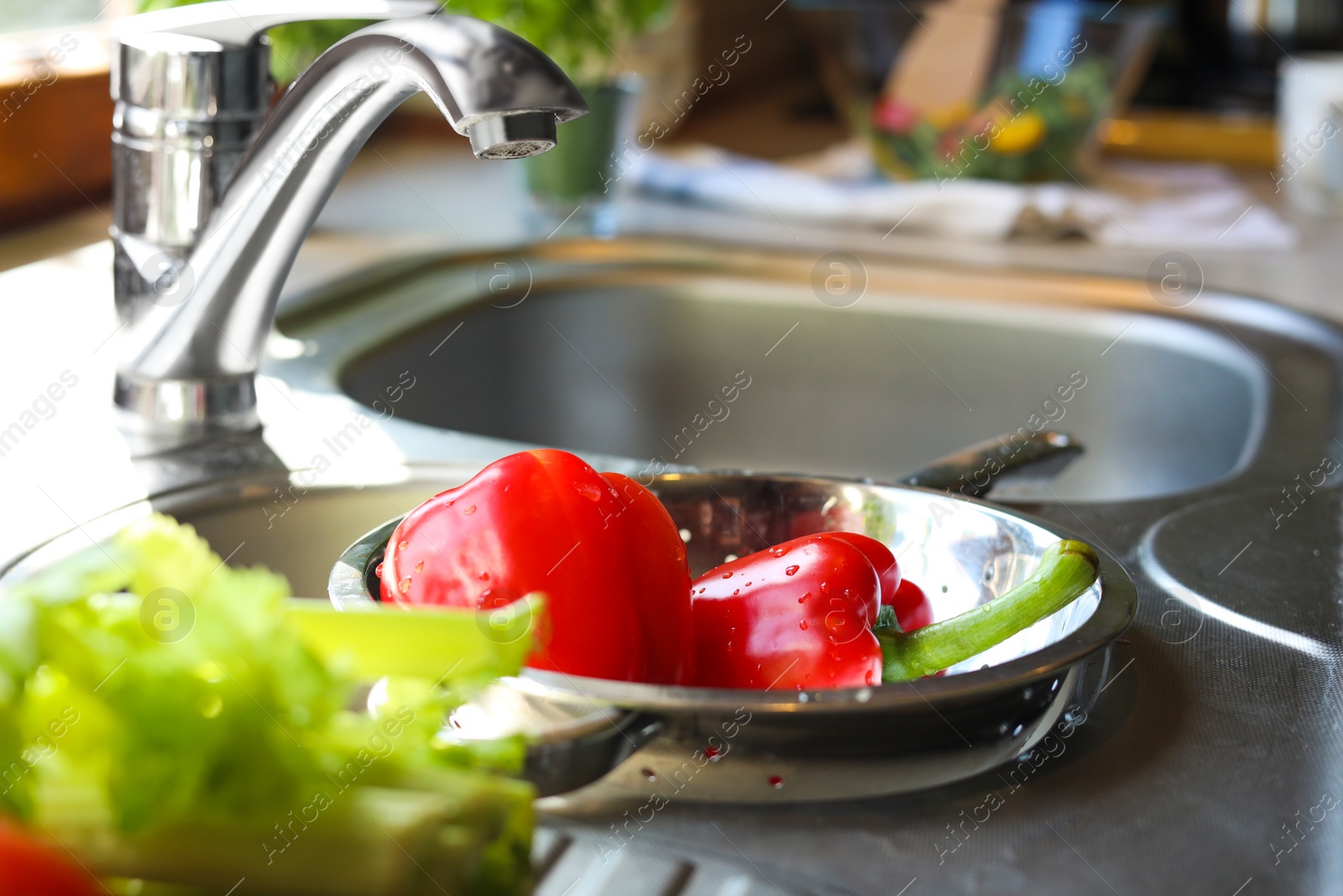 Photo of Colander with fresh bell peppers in kitchen sink