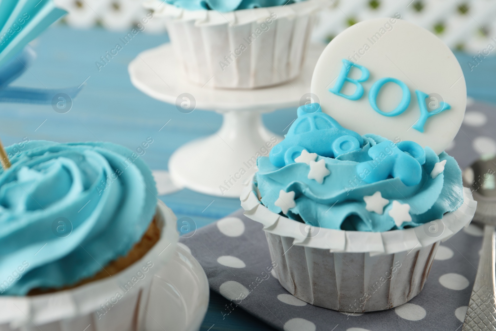 Photo of Delicious cupcakes with light blue cream and toppers for baby shower on table, closeup