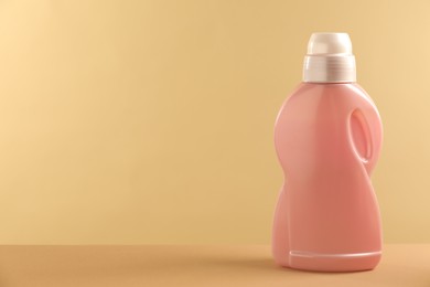 Bottle with detergent on beige background, space for text