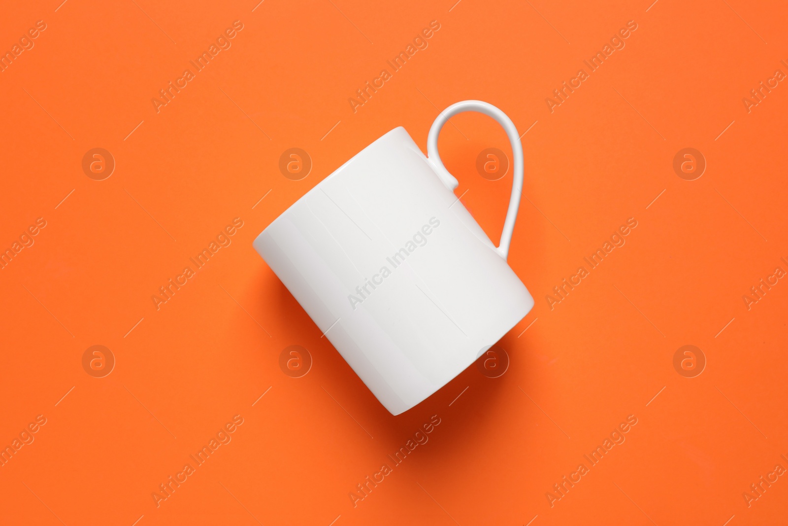 One white ceramic mug on orange background, top view Photo of One white ceramic mug on orange background, top view