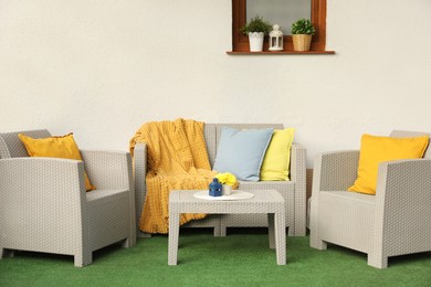 Photo of Beautiful rattan garden furniture, soft pillows, blanket and yellow chrysanthemum flowers outdoors