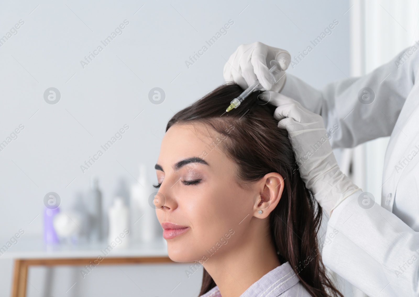 Photo of Young woman with hair loss problem receiving injection in salon