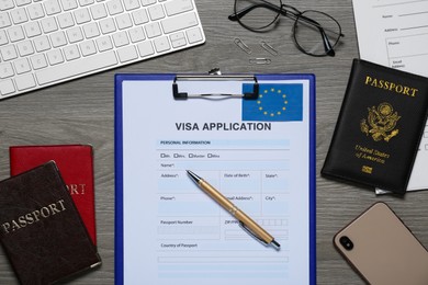 Photo of Visa application form for immigration to European Union, passports and stationery on wooden table, flat lay