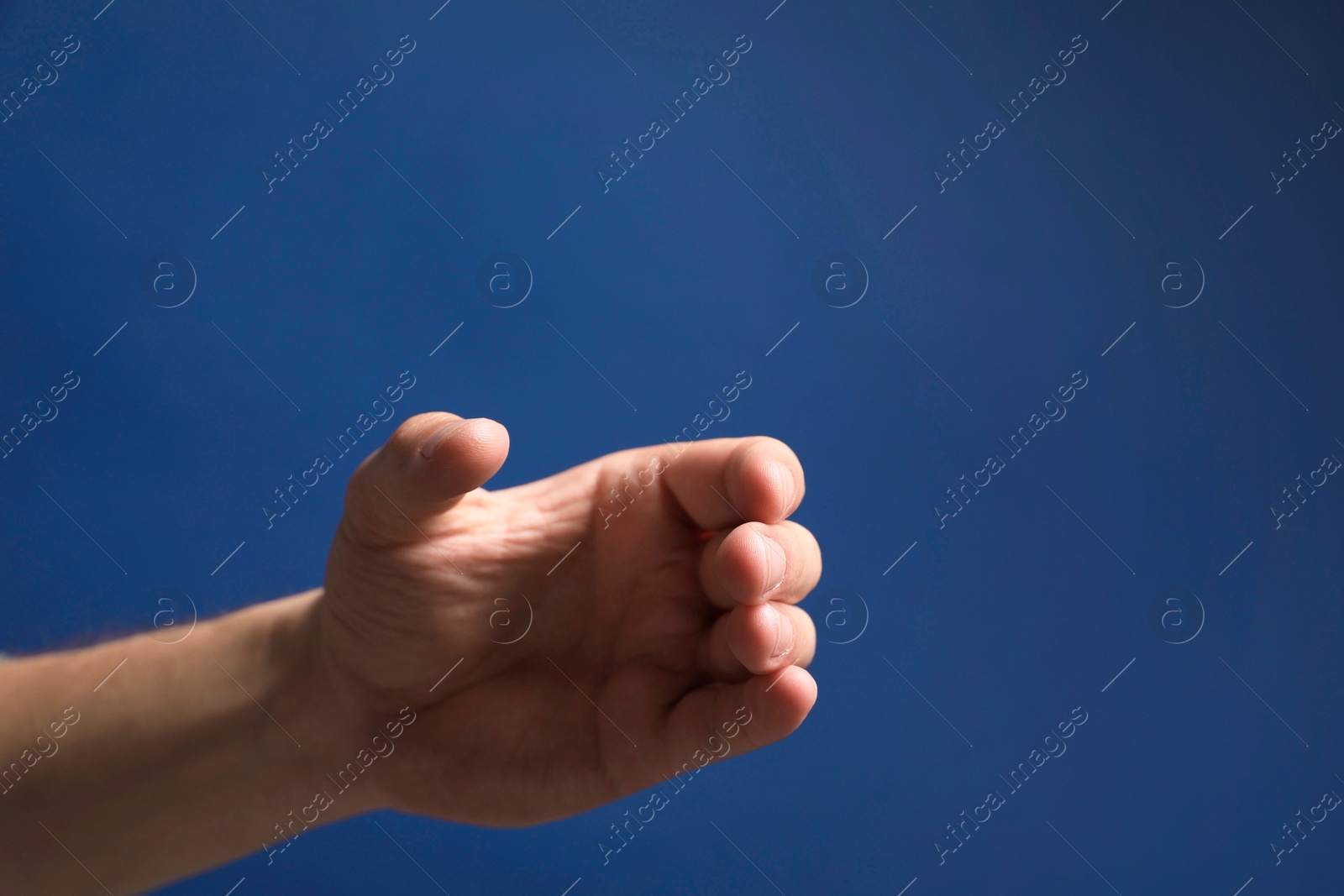 Photo of Man holding something in hand on blue background, closeup