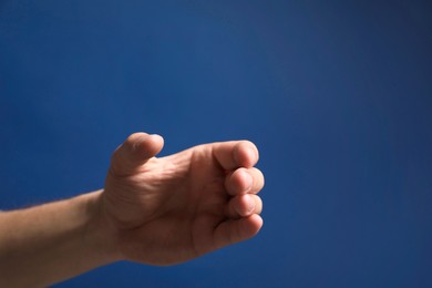 Man holding something in hand on blue background, closeup