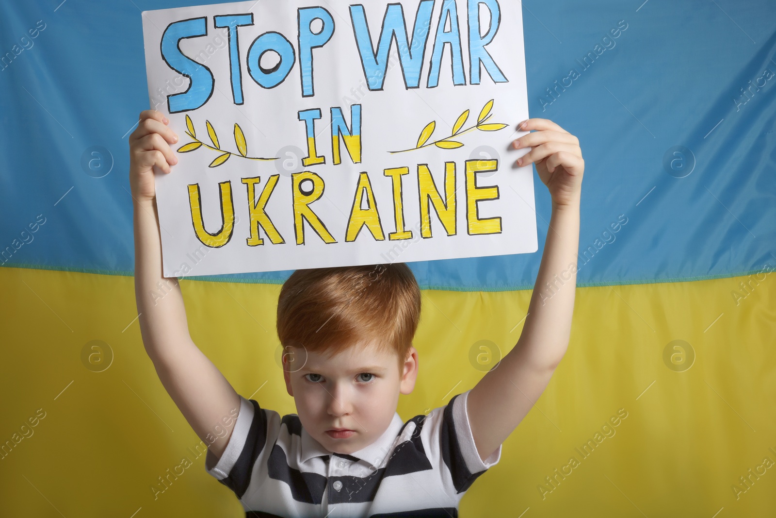 Photo of Boy holding poster Stop War in Ukraine against national flag