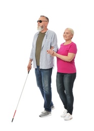 Photo of Mature woman helping blind person with long cane on white background