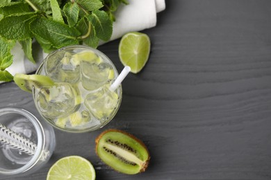 Photo of Glass of refreshing drink with kiwi and ingredients on gray wooden table, flat lay. Space for text