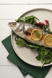 Photo of Baked fish with spinach and lemon on white wooden table, top view