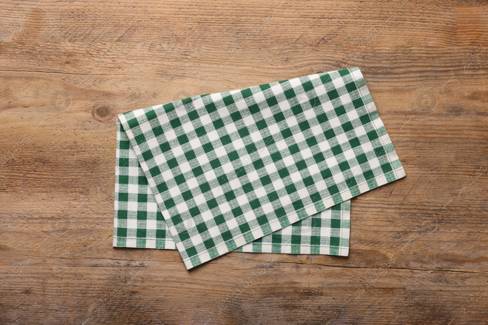 Photo of Checkered tablecloth on wooden table, top view