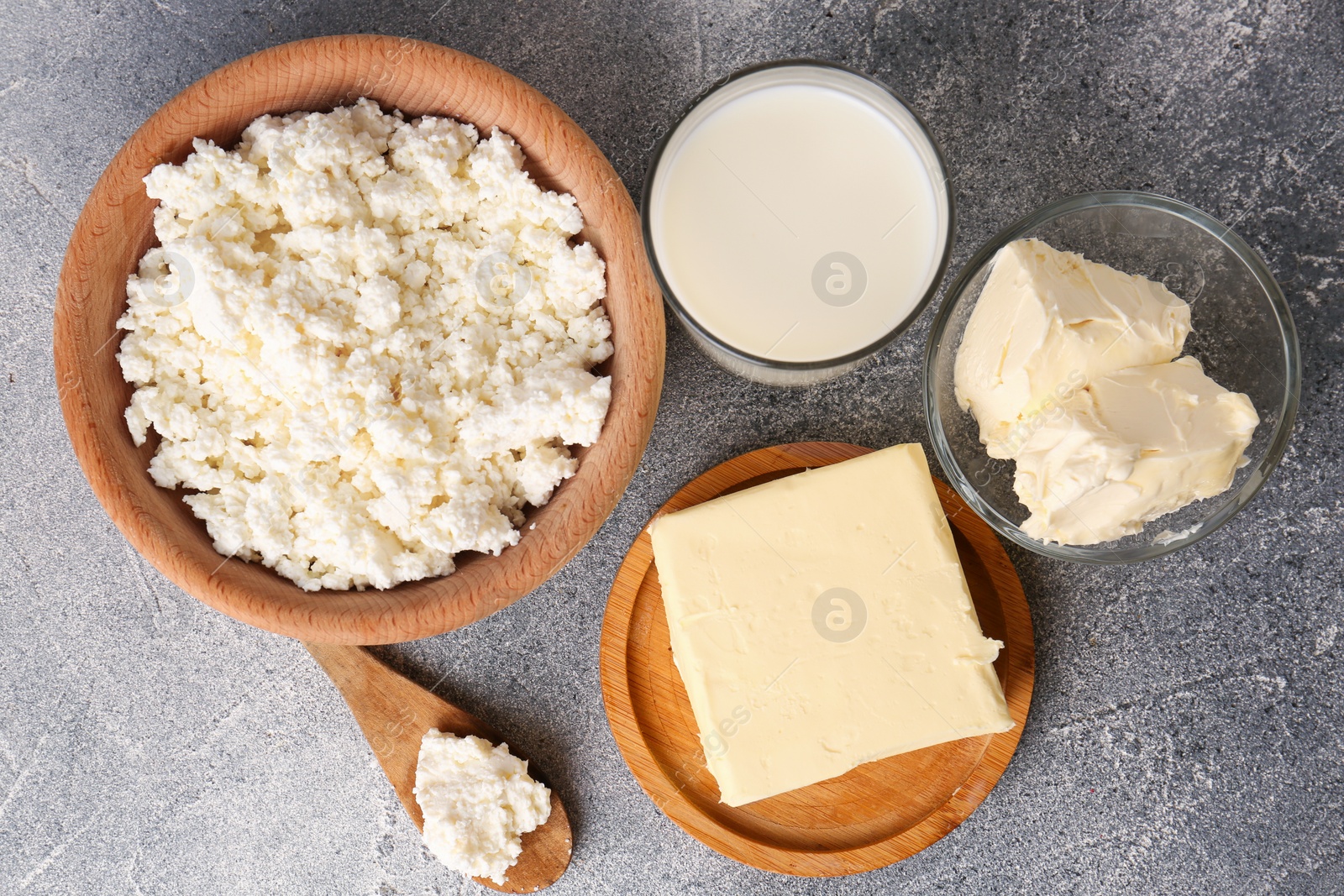 Photo of Tasty homemade butter and dairy products on grey table, flat lay