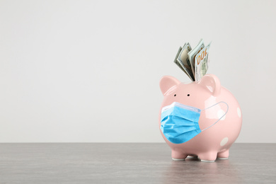 Piggy bank with dollar banknotes and face mask on table against white background. Space for text