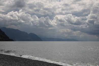 Photo of Picturesque viewbeautiful sea shore and hills under gloomy sky with fluffy clouds