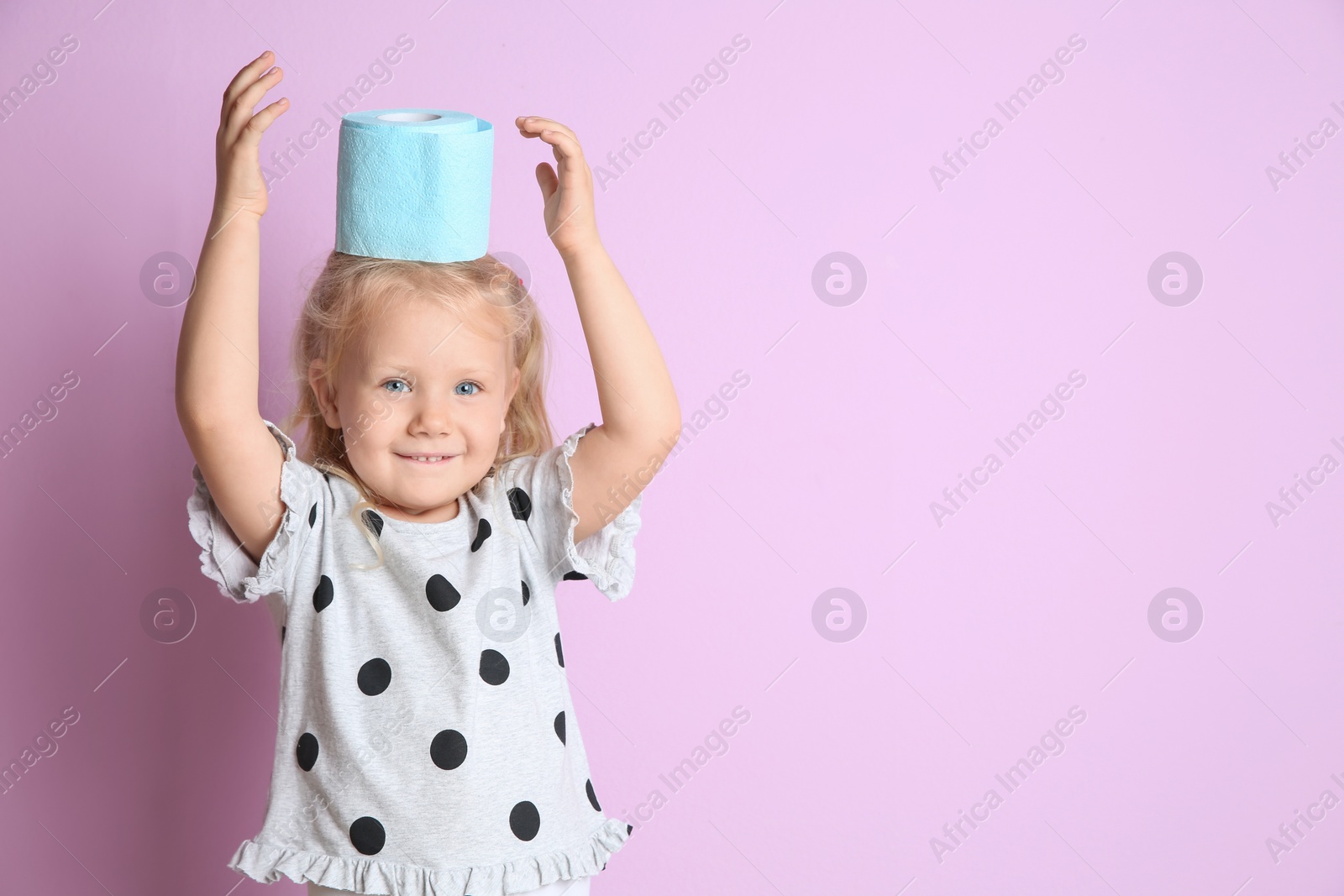 Photo of Cute little girl with toilet paper roll on color background. Space for text
