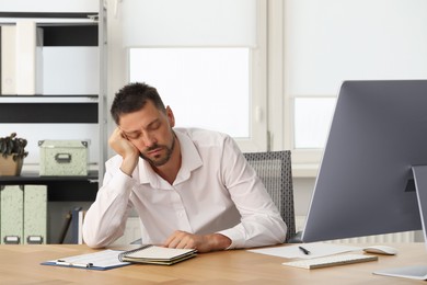 Photo of Sleepy man snoozing at workplace in office