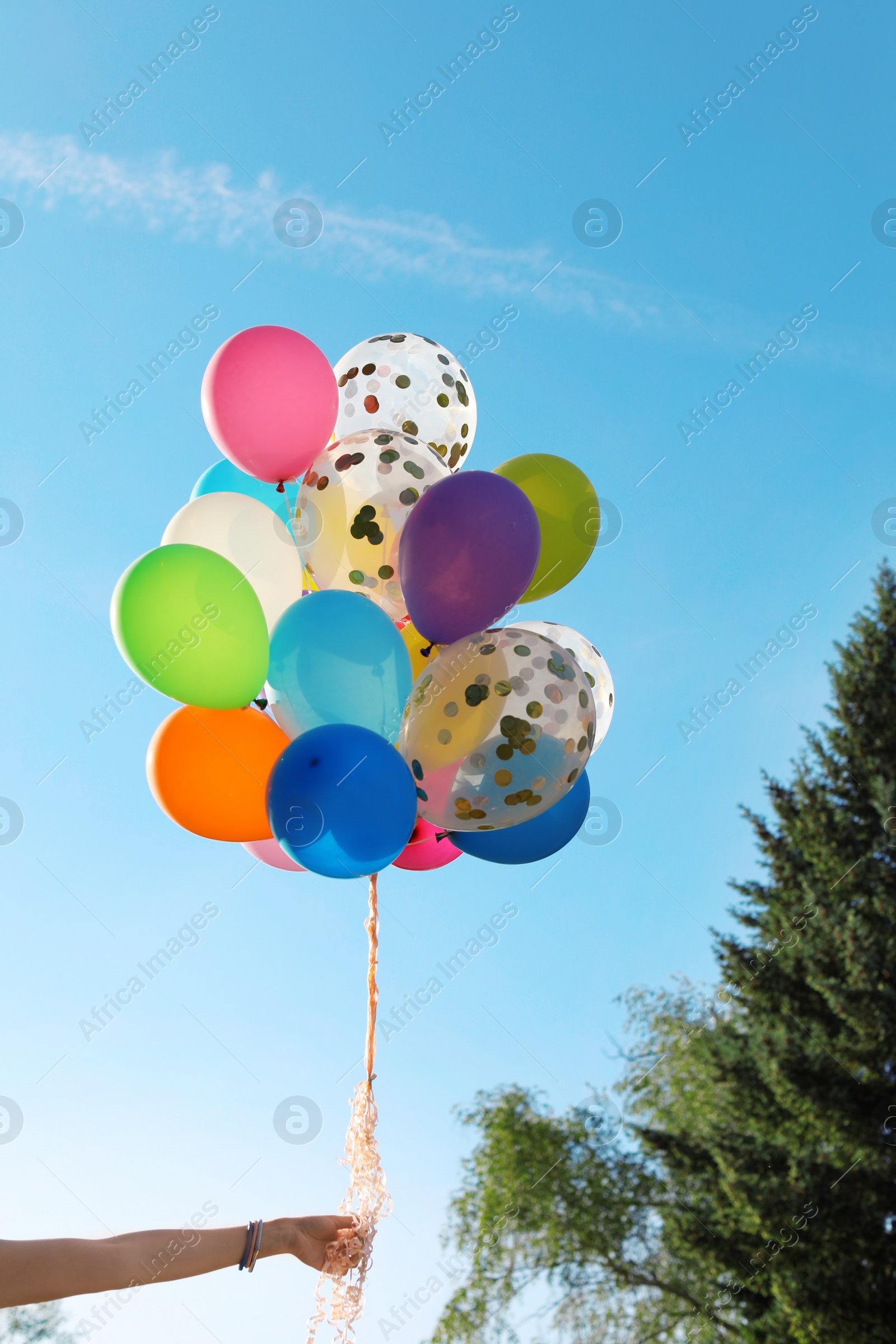 Photo of Young woman with colorful balloons outdoors on sunny day