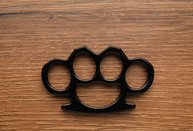 Black brass knuckles on wooden background, top view