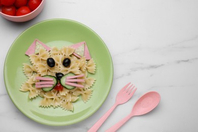Photo of Creative serving for kids. Plate with cute cat made of tasty pasta, vegetables and sausage on white marble table, flat lay. Space for text