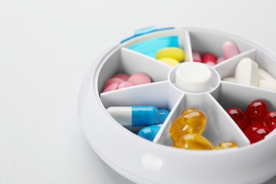 Photo of Plastic box with different pills on light grey background, closeup