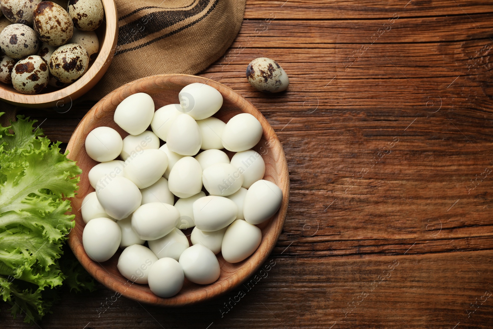 Photo of Unpeeled and peeled boiled quail eggs on wooden table, flat lay. Space for text