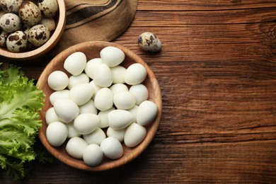 Photo of Unpeeled and peeled boiled quail eggs on wooden table, flat lay. Space for text