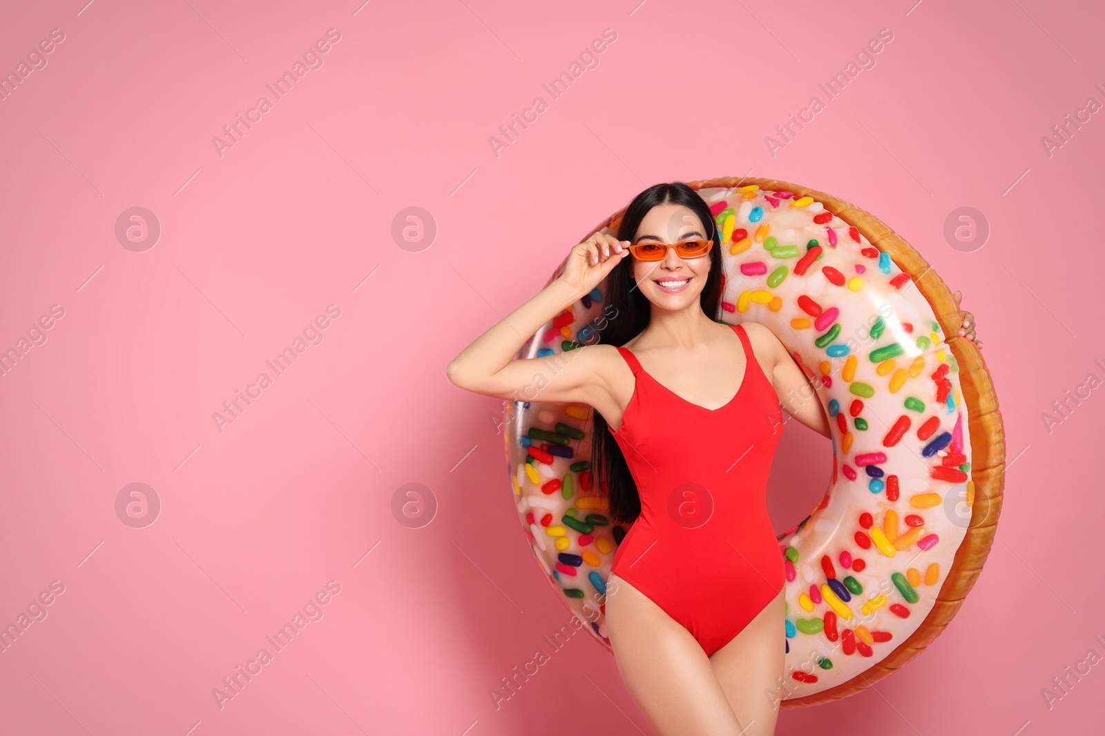 Photo of Young woman with stylish sunglasses holding inflatable ring against pink background. Space for text