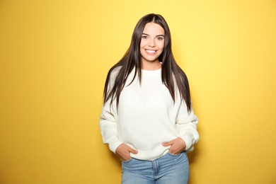 Image of Happy young woman wearing warm sweater on yellow background