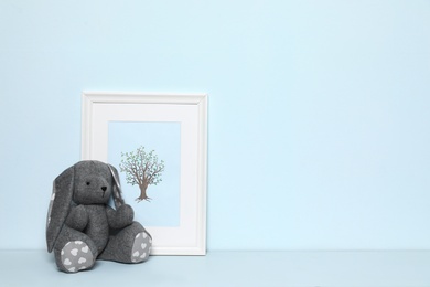 Photo of Soft rabbit and picture on white background, space for text. Child room interior decor