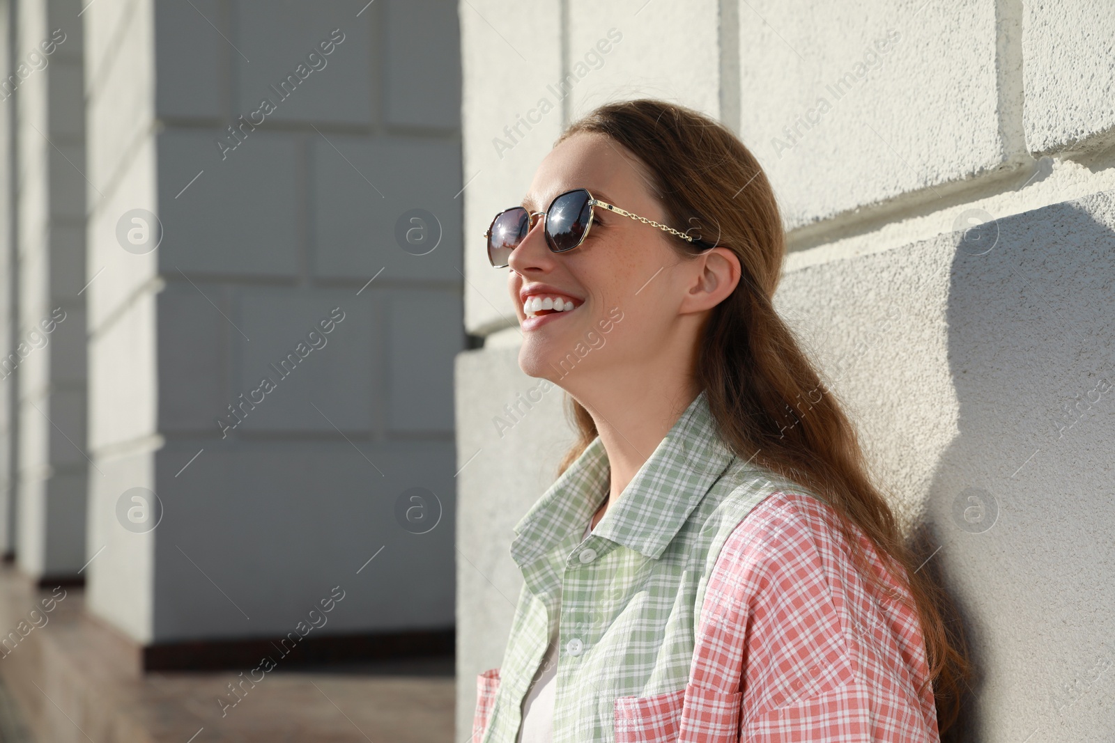 Photo of Smiling woman in sunglasses near building outdoors. Space for text