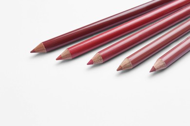 Different lip pencils on white background, closeup. Cosmetic product