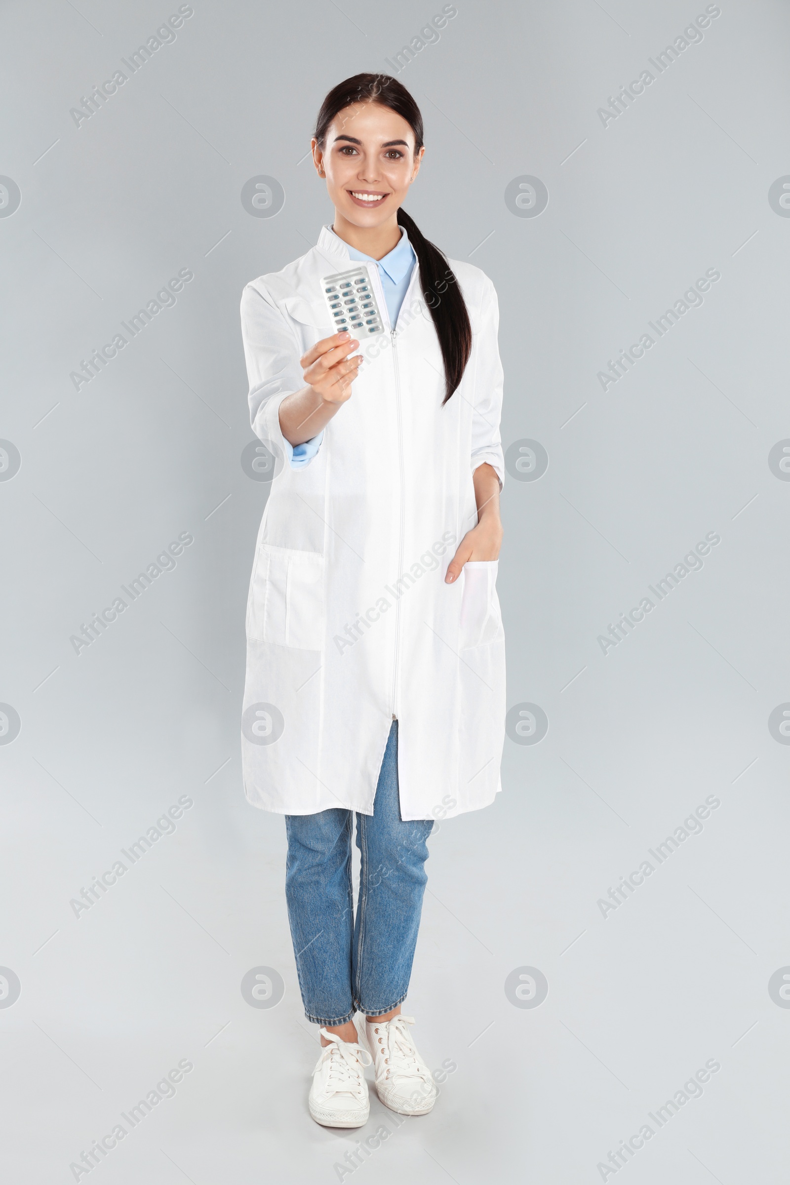 Photo of Professional pharmacist with pills on light grey background