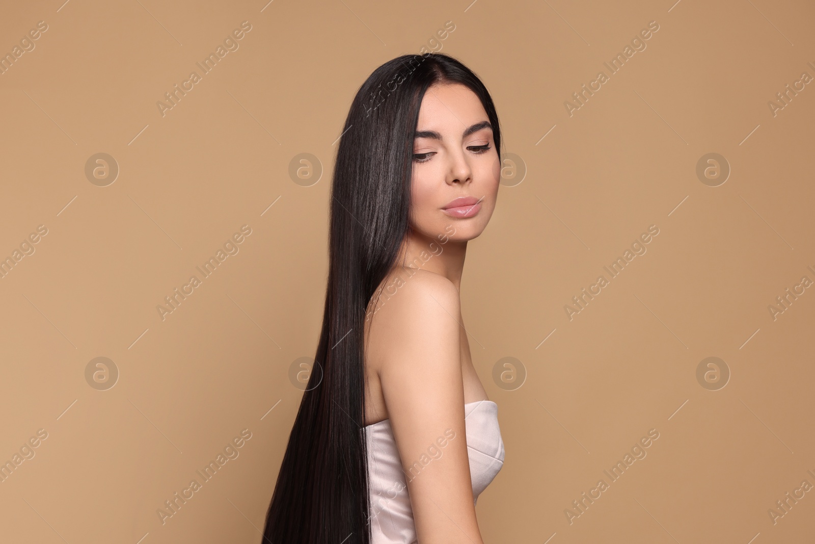 Photo of Portrait of beautiful young woman with healthy strong hair on beige background