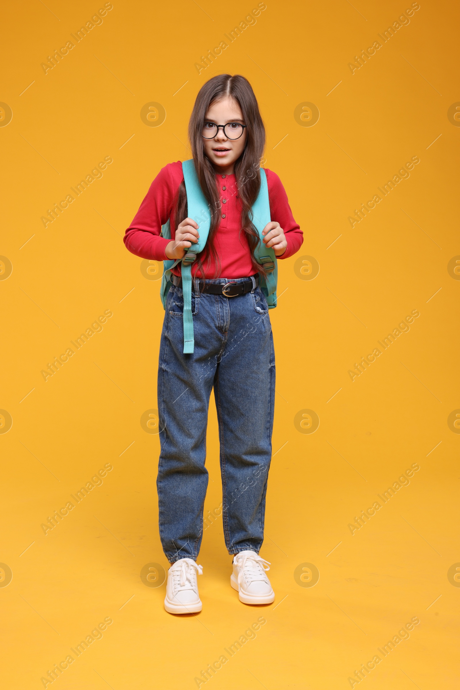 Photo of Cute schoolgirl in glasses on orange background