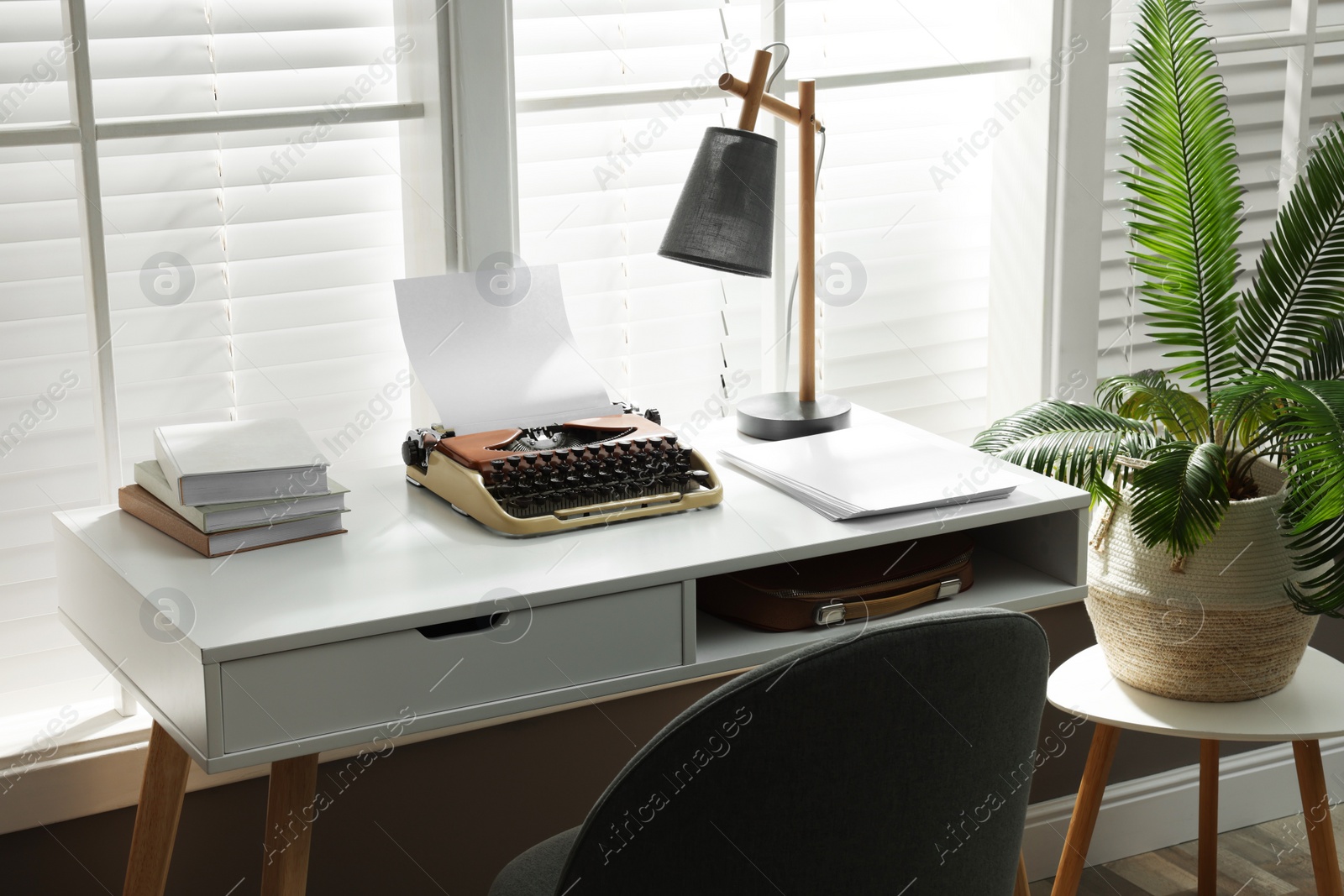 Photo of Comfortable writer's workplace with typewriter on desk in front of window