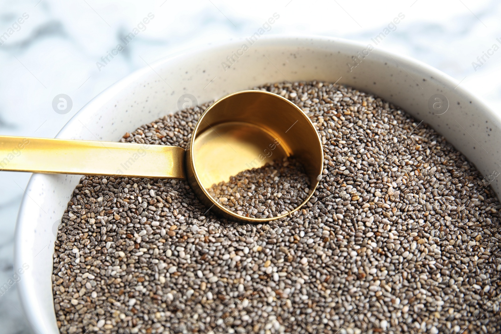 Photo of Bowl and scoop with chia seeds on table, closeup