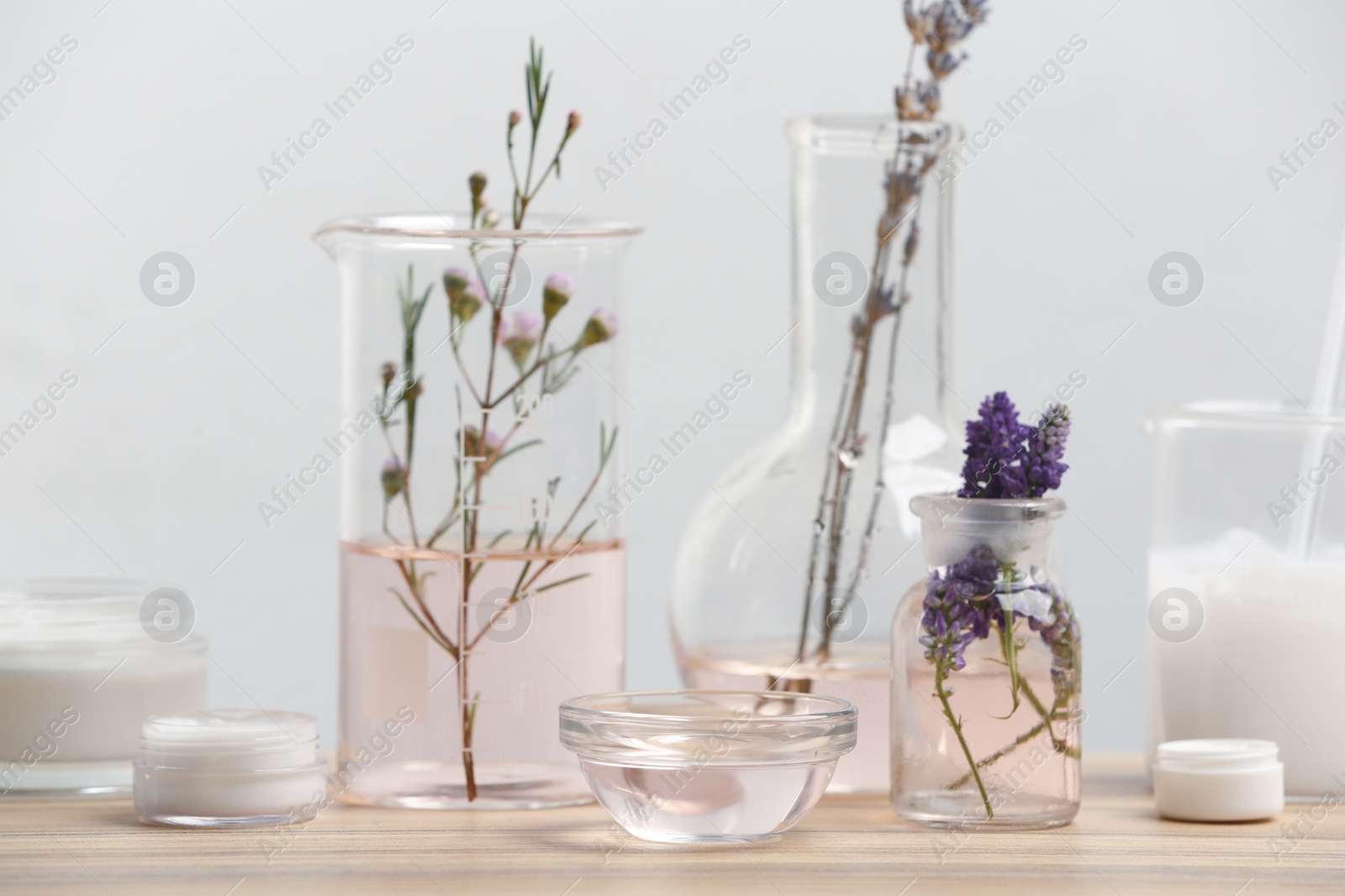 Photo of Herbal cosmetic products, laboratory glassware and ingredients on wooden table