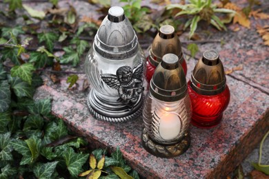 Photo of Grave lanterns and ivy near tombstone in cemetery