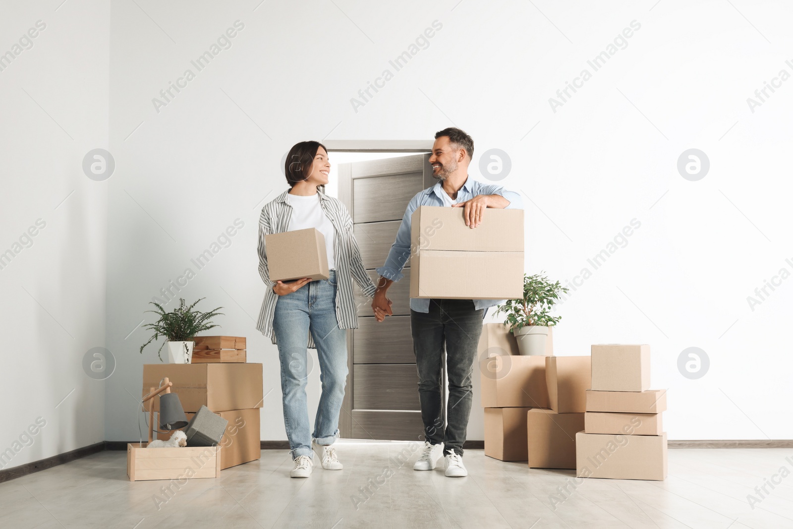 Photo of Happy couple with moving boxes entering in new apartment