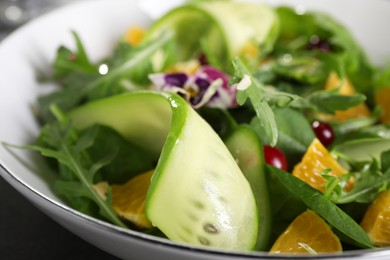 Photo of Delicious salad with cucumber and orange slices in bowl, closeup