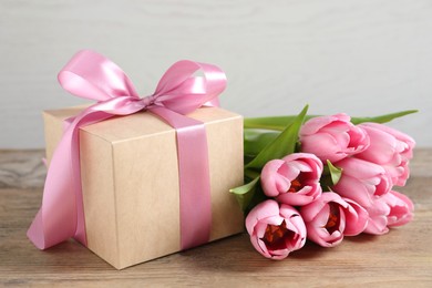 Gift box and beautiful tulip flowers on wooden table