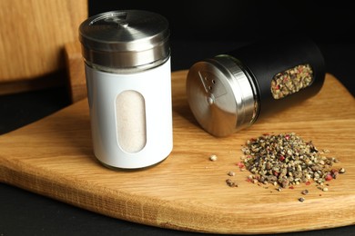 Photo of Salt and pepper shakers on black table, closeup