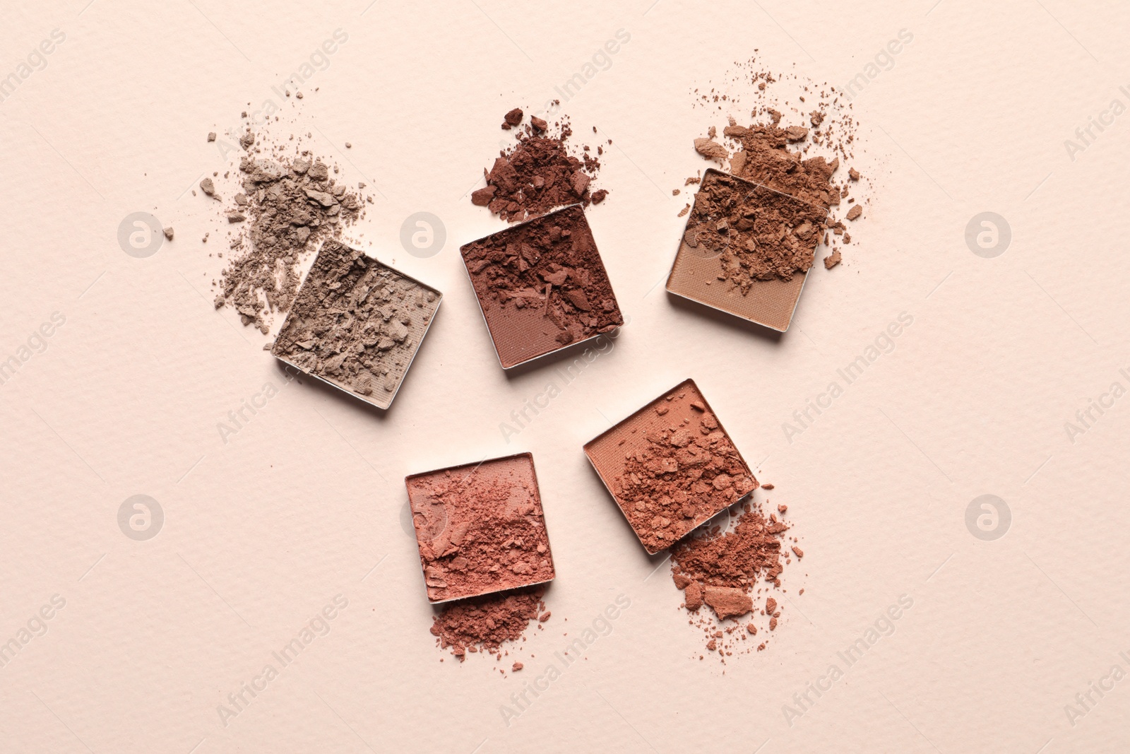 Photo of Different crushed eye shadows on beige background, flat lay