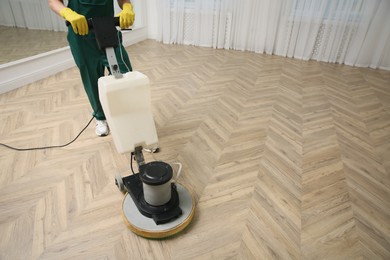 Photo of Professional janitor cleaning parquet floor with polishing machine indoors, closeup. Space for text
