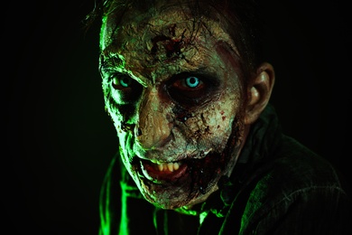 Photo of Scary zombie on dark background. Halloween monster