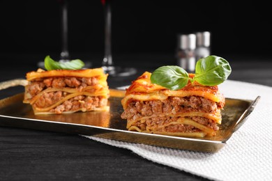 Photo of Delicious cooked lasagna served on black table